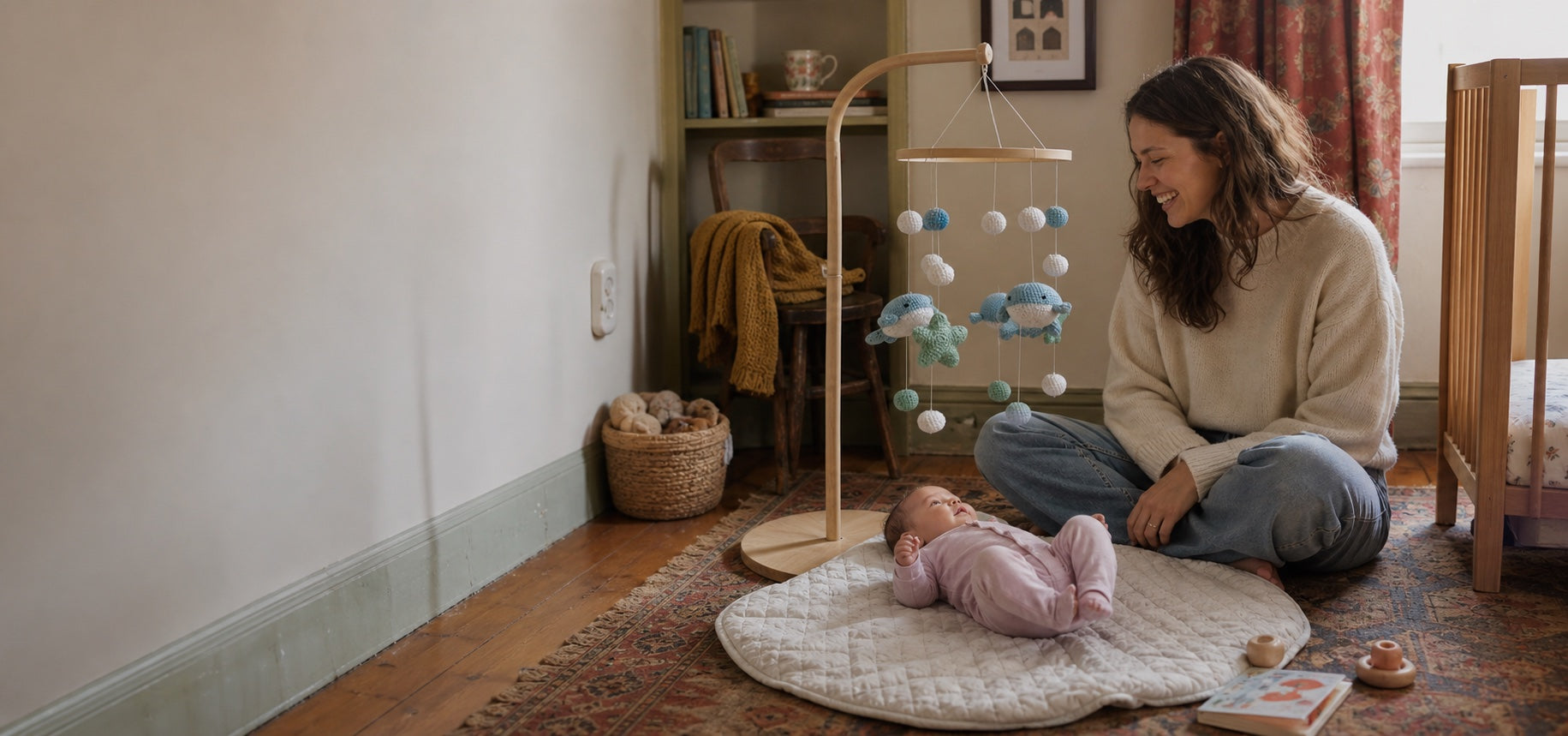 Baby enjoying supervised floor time beneath an Aven and Oak whale mobile