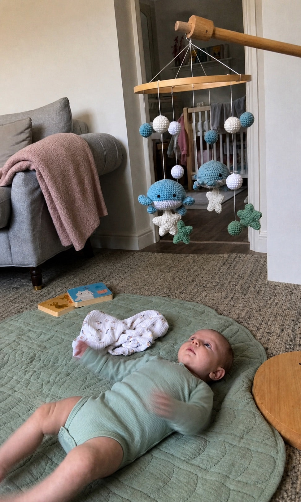 Baby watching an Aven and Oak whale mobile from a play mat